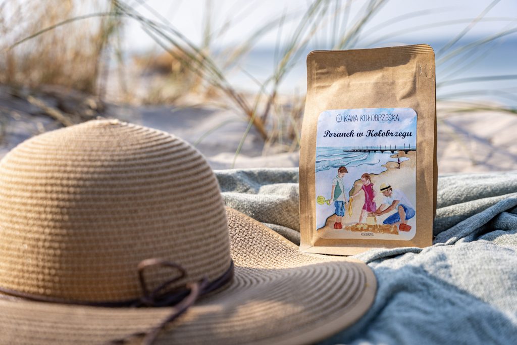 paczka kawy Poranek w Kołobrzegu na plaży obok słomkowego kapelusza