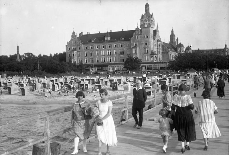 spacerowicze na molo w Kolbergu w 1930 roku, w tle dom zdrojowy i plaża z koszami