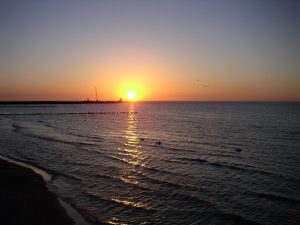 zachód słońca nad Bałtykiem w Kołobrzegu, słońce przy falochronie portu